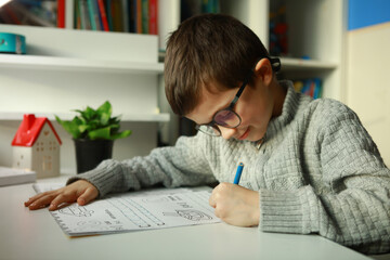 Naklejka premium the boy is learning to write letters.The boy with glasses is doing his homework at home