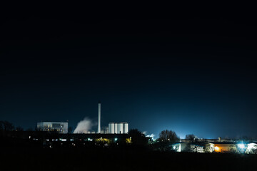 Illuminated Industrial Factory at Night with Smoke and Bright Lights