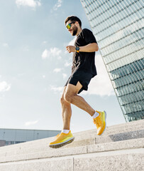 Young man jogging down steps in an urban area during a sunny day