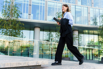 Professional woman walking confidently outside a modern office building during daytime