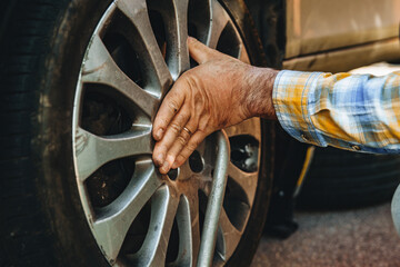 Individual inspects car tire in an automotive maintenance activity on a sunny day