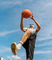 Basketball player performs an impressive jump shot during a bright day at an urban court