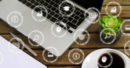 Image of network of icons over laptop and cup of coffee on desk