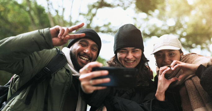 Friends, hiking and selfie in a forest with peace, heart or hands gesture while bonding in nature. Phone, profile picture and group of people happy in a jungle for adventure, freedom and trekking fun