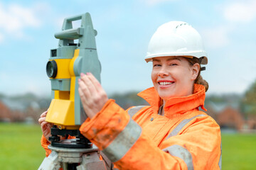 Professional female surveyor using modern equipment outdoors on a clear day in a rural area while...