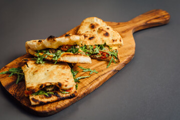 Pizza-Sandwich with Veal and Roasted Pepper – A delicious fusion of seared veal slices, roasted pepper, sun-dried tomatoes, arugula, parmesan cheese, cheddar, capers, and pesto sauce 