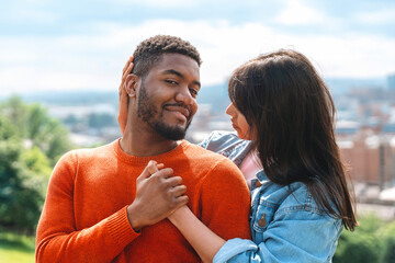 Fototapeta premium Couple enjoying a tender moment outdoors with a scenic urban backdrop in the daylight