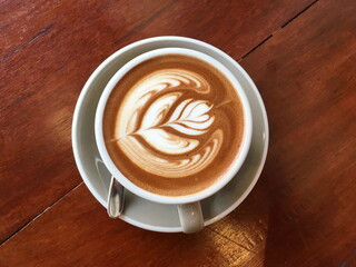 Top view of Cappucino coffee cup with latte art on wood background.