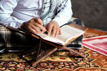 Indonesian Muslim man with curly hair who is very focused on reading the Quran, Muslims, the...