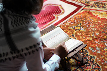 Indonesian Muslim man with curly hair who is very focused on reading the Quran, Muslims, the...