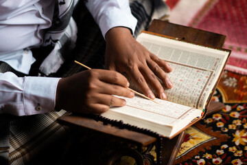 Indonesian Muslim man with curly hair who is very focused on reading the Quran, Muslims, the...