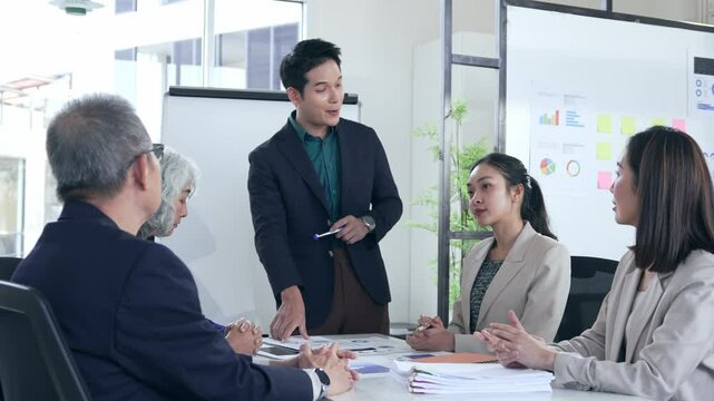Professional Asian business team collaborating during strategic meeting, sharing innovative project insights and discussing growth opportunities in modern corporate workspace