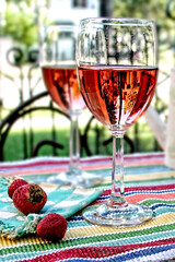 Wine glasses with rose win on a patio table heat two strawberries
