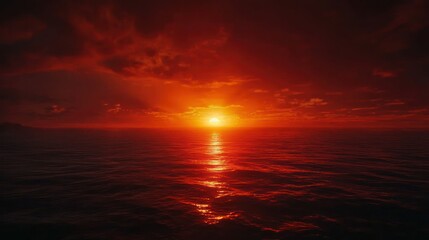 Fototapeta premium A dramatic red sunset over the ocean, with the horizon glowing intensely as the day ends.