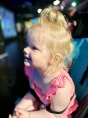 Petite fille blonde vêtue de rose regardant avec attention