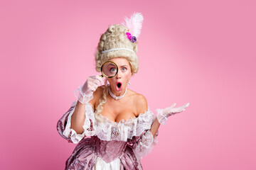 Elegant woman in baroque-style attire holding a magnifying glass with a surprised expression, pink background