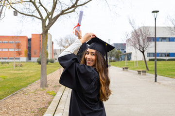 Happy graduate raising diploma in university campus