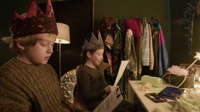 Caucasian girl and boy spending time in theatre dressing room, repeating their lines before performance