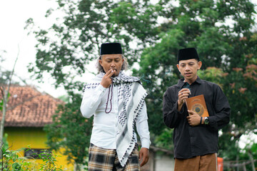 Young Indonesian Muslim male student wearing a skullcap studying with an ustadz, Ramadhan concept.