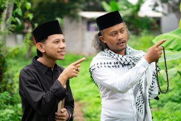 Young Indonesian Muslim male student wearing a skullcap studying with an ustadz, Ramadhan concept.