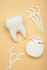 White healthy tooth with dental floss on beige. Oral dental care products, hygiene cleaning personal use lifestyle concept