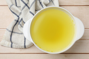 Tasty chicken bouillon in bowl on wooden table, top view