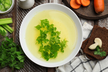 Tasty chicken bouillon served on wooden table, flat lay