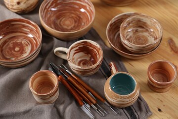 Different beautiful pottery and set of clay crafting tools on wooden table