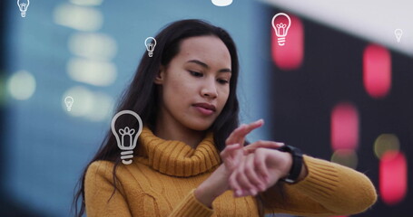 Image of lightbulbs over biracial woman using smartwatch