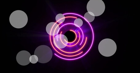 Image of light spots over neon circles on black background
