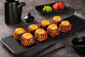 Delicious sushi rolls with spicy topping on elegant black plate