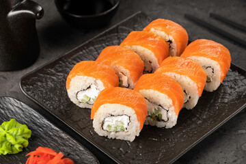 Fresh salmon sushi rolls with cream cheese and avocado on black plate