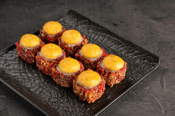 Appetizing sushi rolls with spicy sauce on black ceramic dish