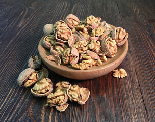 shelled walnuts in a wooden plate on a wooden table