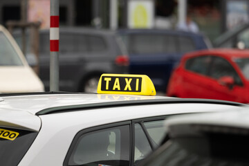 Taxi sign on a car close-up in Austria. Driver waiting in a busy urban area. The yellow symbol is mounted to the roof. Transportation service in the inner city for tourists.