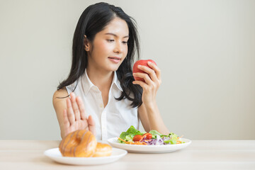 Diet, dieting, happy asian young woman, girl hand push out, deny sweet donut, doughnut on plate, choose red apple and green vegetable salad, eat food for good healthy, female getting weight loss.
