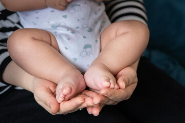 Close-up of a mother holding her baby's foot, showing care and parent-child bond.