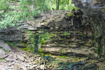 Hilton Falls cliff face showing layered limestone rock formation with small trickling waterfalls...