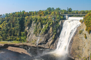 Magnificent Montmorency Falls cascading down steep rocky cliffs surrounded by vibrant autumn foliage