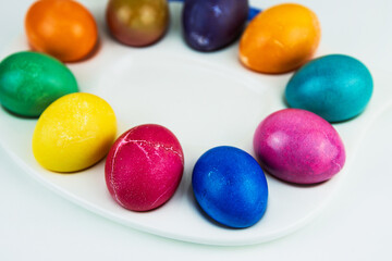 Colorful dyed easter eggs arranged on a white plate. multicolored eggs in bright hues of yellow, purple, green, and blue. Color contrast, creativity, holiday decoration. Copy space. Selective focus