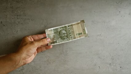 Hand holding indian 500 rupee note on concrete background, illustrating currency concept.