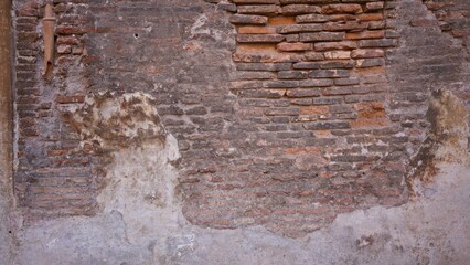 Textured weathered brick wall showcases rugged rustic charm, ideal for backgrounds in urban architectural design and construction projects.