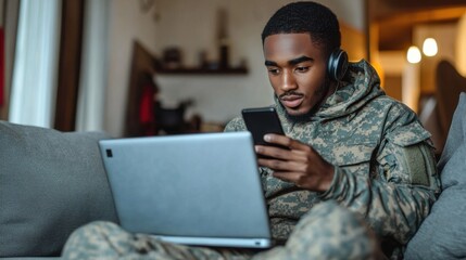 Young soldier relaxing at home using laptop and smartphone