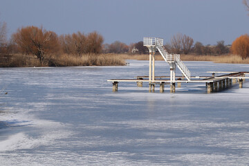 Diving tower in winter. The water is covered with ice.