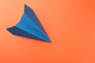 One handmade blue paper plane on orange background, top view. Space for text