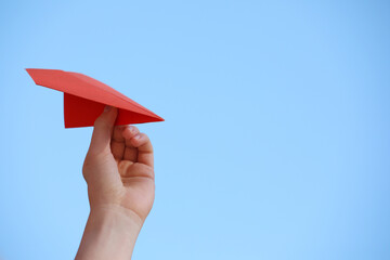 Woman with handmade paper plane against blue sky outdoors, closeup. Space for text