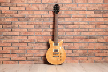 Naklejka premium One modern electric guitar near brick wall