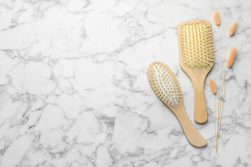 Wooden hair brushes and spikes on white marble background, top view. Space for text