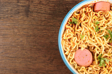 Top view of a part of a bowl with ready-made instant noodles with sausages added.