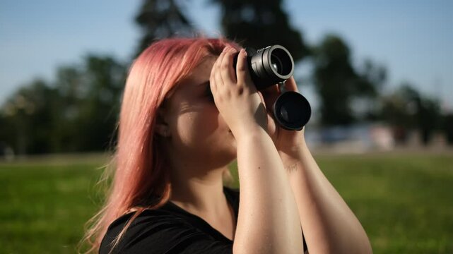 young fat woman looking through monoculars outdoors sunny summer day